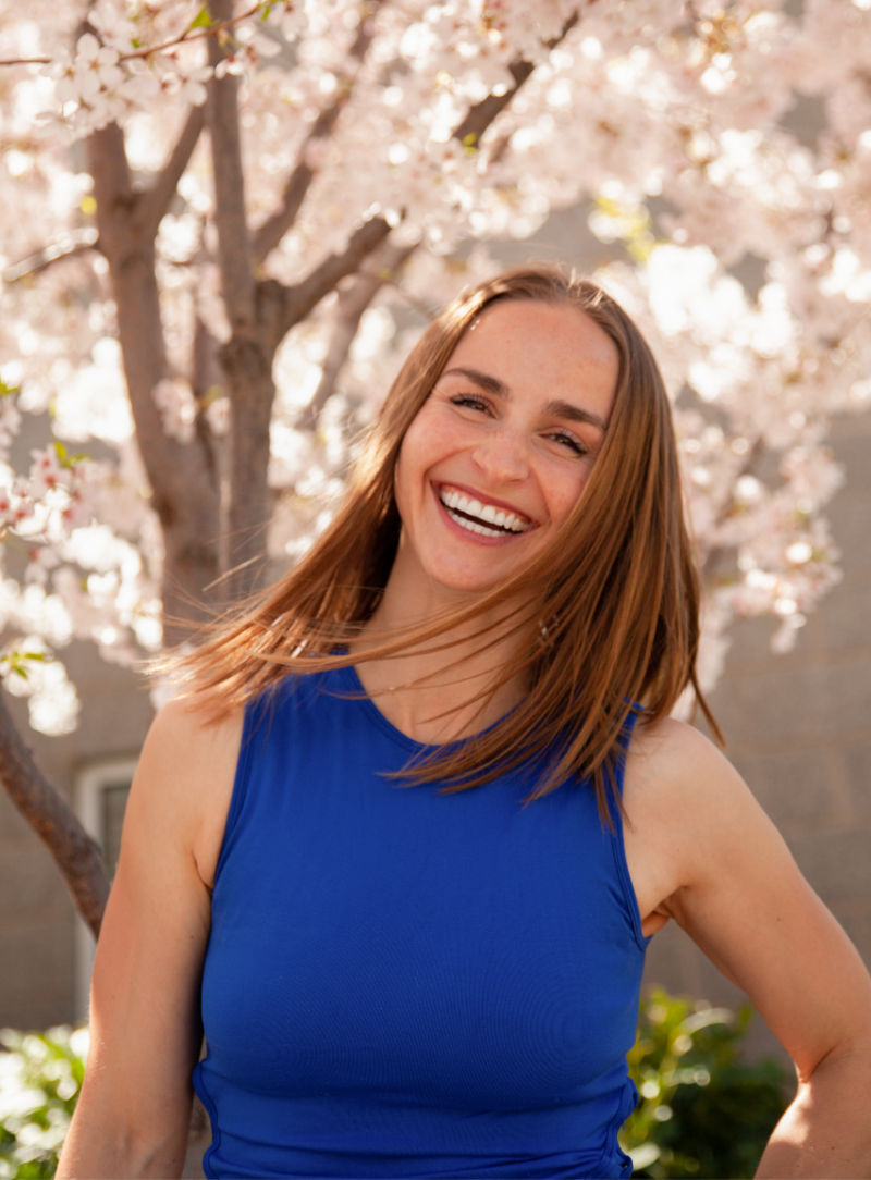 Lexi Coroles smiling beneath flowering trees